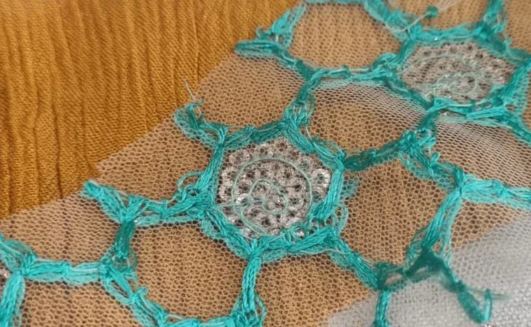 Close-up of delicate turquoise embroidery in honeycomb pattern on golden tulle fabric from Robe Jali Nid d'abeille by ALTER. - Robe Jali Nid d'abeille - S - ALTER EGO