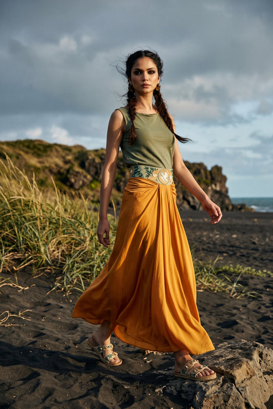 Woman wearing a flowing saffron-orange maxi skirt with a draped waist, paired with a pale green embroidered top on a rocky. - Jupe DOVE - S - ALTER EGO